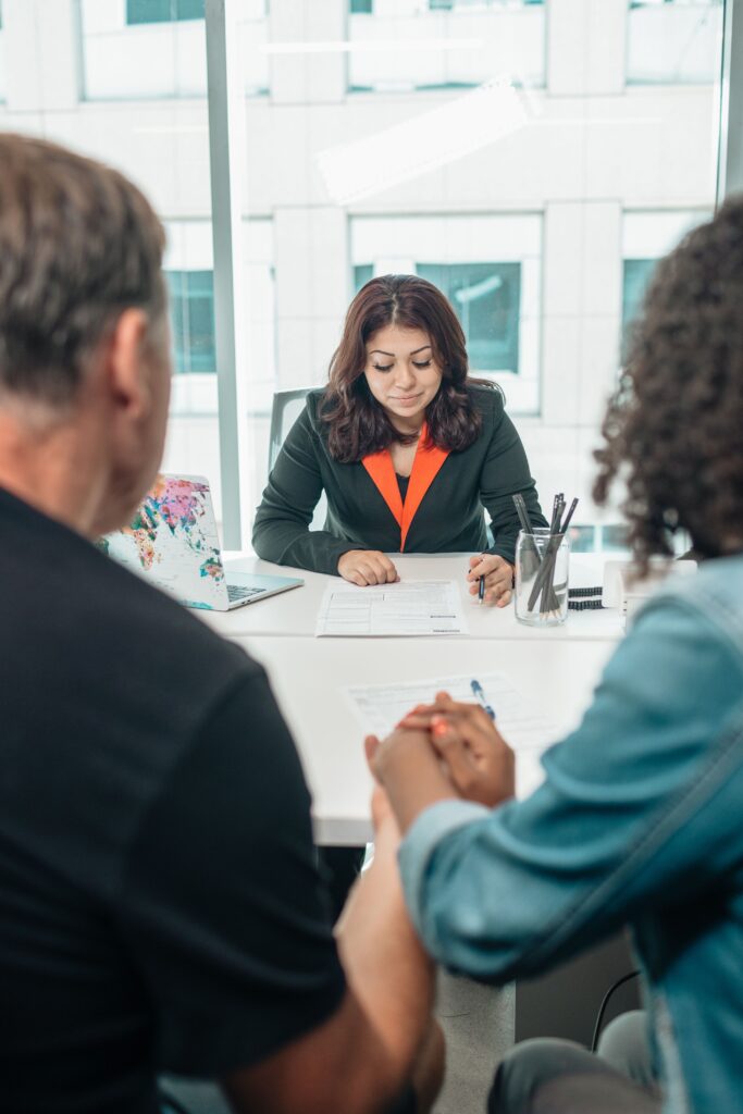 A couple signing adoption papers in an office with a lawyer's assistance.