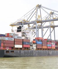 Cargo vessel moored at Kochi, Kerala, India, showcasing global container shipping with cranes in background.